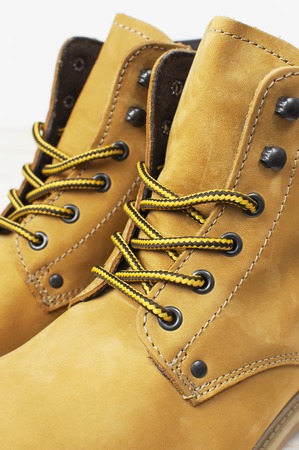 Close-up Yellow men's work boots from natural nubuck leather on wooden white background. Trendy casual shoes, youth style. Concept of advertising autumn winter shoes, sale, shopの写真素材