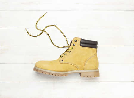 Yellow men's work boots from natural nubuck leather on wooden white background top view flat lay with copy space. Trendy casual shoes, youth style Concept of advertising autumn winter shoes sale shopの写真素材