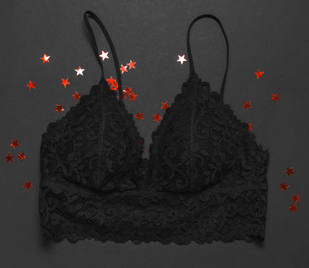 Black lace bra underwear, holographic confetti on dark background top view flat lay. Female essential erotic accessories, fashionable underwear gift for birthday valentines day new year christmasの写真素材