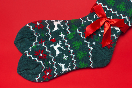 Woolen socks with a Christmas New Year ornament on red background top view flat lay. Holiday concept, Festive socks, presents Xmas. Congratulations background with space for text Clothes for the coldの写真素材
