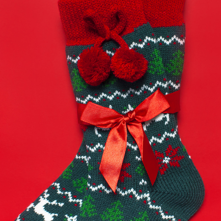 Woolen socks with a Christmas New Year ornament on red background top view flat lay. Holiday concept, Festive socks, presents Xmas. Congratulations background with space for text Clothes for the coldの写真素材