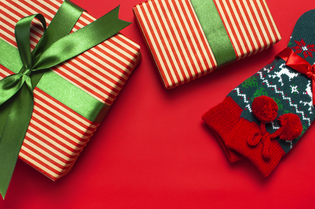 Woolen socks with a Christmas New Year ornament and gift box on red background top view flat lay. Holiday concept, presents Xmas. Congratulations background with space for textの写真素材