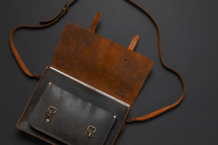 Fashionable concept. Brown leather men's bag on black background top view flat lay with copy space....