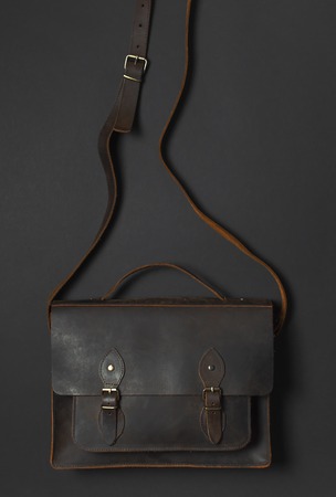 Fashionable concept. Brown leather men's bag on black background top view flat lay with copy space. Briefcase for work, Accessories businessman, stylish men's clothes, business backgroundの写真素材