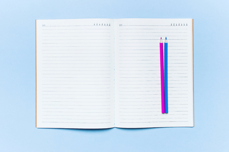 Color pencils and clean notebook in line on blue background top view flat lay copy space. Wooden colored pencils for drawing, objects for creativity, school supplies close-up. Back to school conceptの写真素材