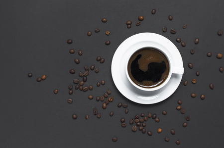 Flat lay cup of black coffee and coffee beans on gray dark background top view copy space. Minimalistic food concept, morning breakfast, time to work, hot drink coffee backgroundの写真素材