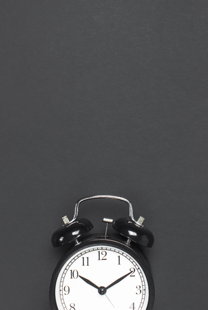 Black retro alarm clock on gray dark background top view Flat lay copy space. Minimalistic background, concept of time, deadline, time to work morningの写真素材