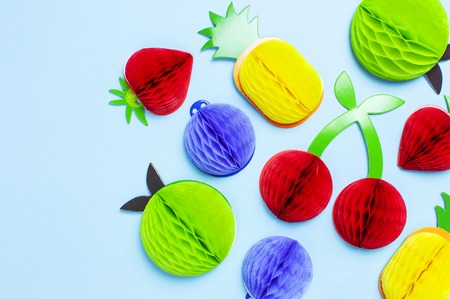 Flat lay bright tropical fruits of paper, strawberry, cherries, pineapple, apple, plum on blue background top view copy space. Minimalistic creative summer food concept, origami paper fruit.の写真素材