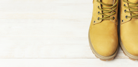 Close-up Yellow men's work boots from natural nubuck leather on wooden white background. Trendy casual shoes, youth style. Concept of advertising autumn winter shoes, sale, shopの写真素材