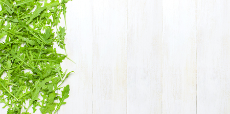 Fresh green arugula leaves, rucola salad on white wooden rustic background top view Flat lay with place for text. Rocket salad or arugula, healthy food, diet. Nutrition conceptの写真素材