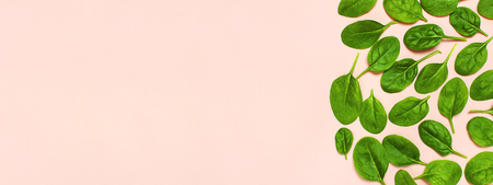 Fresh green spinach leaves on pink background Flat lay top view copy space. Creative food concept. Ingredient for salad. Vegetable design. Healthy lifestyleの写真素材