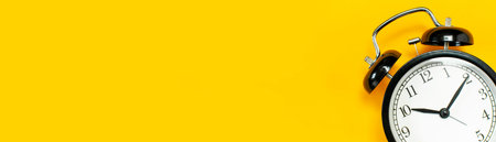 Black retro alarm clock on yellow background top view Flat lay copy space. Minimalistic background,...