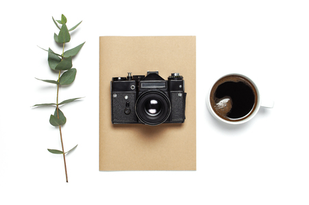 Old retro camera notebook diary cup of coffee eucalyptus leaves on white background. Flat lay top view copy space. Stylish minimal composition artwork mockup Feminine desk workspace.の写真素材