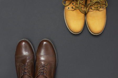 Classic brown leather mens shoes and Yellow mens work boots from natural nubuck on gray black background top view flat lay copy space. Fashion male concept, genuine leather shoes, sale, shopの写真素材