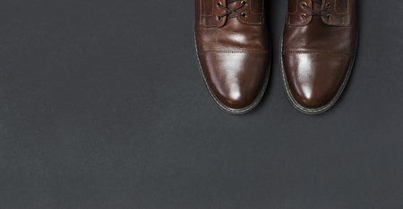 Classic brown leather men's shoes on gray black background top view flat lay with copy space. Fashion male concept, genuine leather shoes. Store advertisement, sale, shopの写真素材
