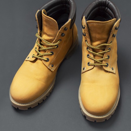 Yellow men's work boots from natural nubuck leather on gray black background. Trendy casual shoes, youth style. Concept of advertising autumn winter shoes, sale, shopの写真素材