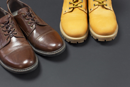 Classic brown leather men's shoes and Yellow men's work boots from natural nubuck on gray black background top view flat lay copy space. Fashion male concept, genuine leather shoes, sale, shopの写真素材