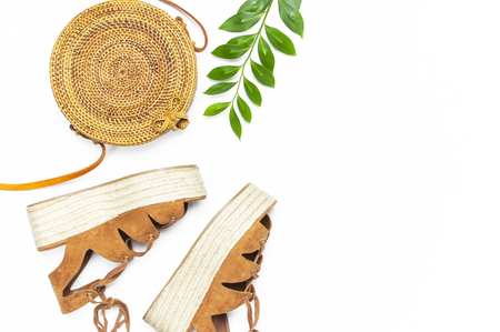 Fashionable handmade natural organic rattan bag, sandals, green twig on white background. Ladies bag Female fashion background. Flat lay, top view, copy space. Ecobags from Bali. Stylish rattan bag.の写真素材
