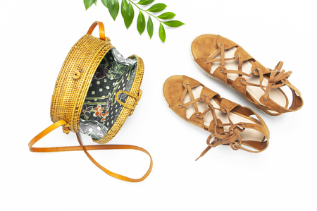 Fashionable handmade natural organic rattan bag, sandals, green twig on white background. Ladies bag Female fashion background. Flat lay, top view, copy space. Ecobags from Bali. Stylish rattan bag.の写真素材