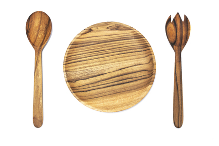Empty round wooden plate, fork, spoon isolated on white background top view. Handcrafted cooking utensils, dishes from natural materials, kitchen interior itemsの写真素材
