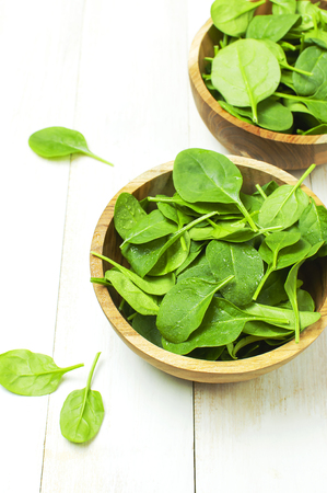 Fresh green spinach leaves on wooden bowl on white wooden rustic background Selective focus copy space. Baby young spinach leaves, Ingredient for salad, healthy food, diet. Nutrition conceptの写真素材