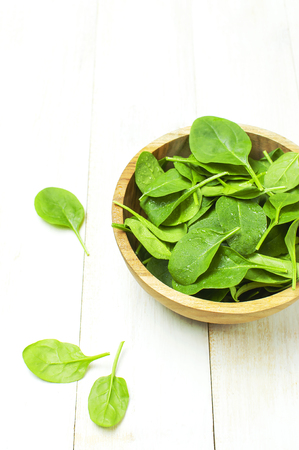Fresh green spinach leaves on wooden bowl on white wooden rustic background Selective focus copy space. Baby young spinach leaves, Ingredient for salad, healthy food, diet. Nutrition conceptの写真素材