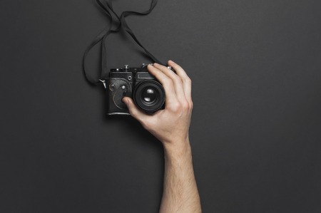Male hands hold old vintage camera on black background top view flat lay with copy space. Concept for the photographer, old photographic equipment, minimalistic style.の写真素材