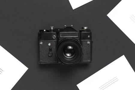 Old retro vintage camera, white blank photo cards on black background top view flat lay with copy space. Concept for the photographer, old photographic equipment, minimalistic style selective focus.の写真素材
