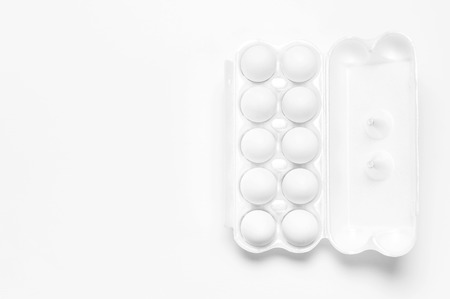 White chicken eggs in white packaging on light background top view flat lay copy space. Eggs in box, natural healthy food and organic farming concept. Creative food minimalistic background, Easter.の写真素材