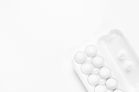 White chicken eggs in white packaging on light background top view flat lay copy space. Eggs in box, natural healthy food and organic farming concept. Creative food minimalistic background, Easter.の写真素材