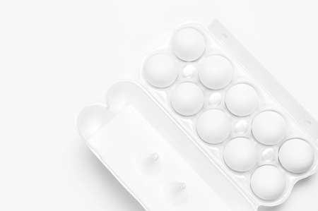 White chicken eggs in white packaging on light background top view flat lay copy space. Eggs in box, natural healthy food and organic farming concept. Creative food minimalistic background, Easter.の写真素材
