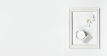 Hand or body cream, orchid flower, cotton pads, Photo frame on light background top view flat lay. Cosmetics SPA branding mock-up, Natural organic beauty product concept, Minimalism cosmetics style.の写真素材