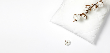 Soft white quilted pillow and branch of cotton on light background top view. Clean pillow, interior item, bedding mockup design template.の写真素材