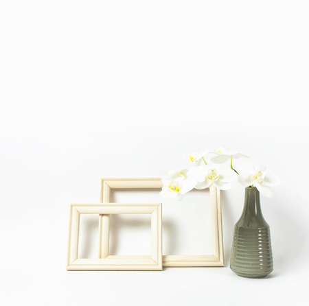 White Phalaenopsis orchid flowers in gray vase and wooden photo frames on white background. Tropical flower, branch of orchid. Holiday, Women's Day, Flower Card flat lay. Interior details Mockup.の写真素材