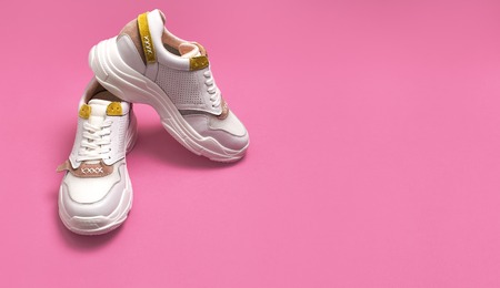 White female sneakers on bright pink background. Fashion blog or magazine concept. Women shoes, trendy sneakers, fashion, style, lifestyle.の写真素材