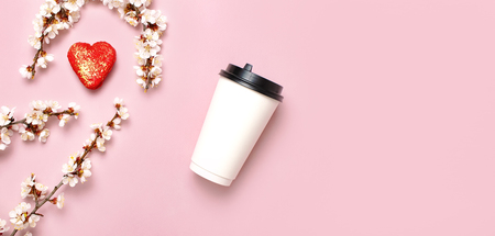 Coffee or tea paper cup, heart-shaped macaroon cakes, spring branches of white flowers on pink background top view flat lay. Take away coffee cup, mockup. Coffee love concept, layout for design.の写真素材