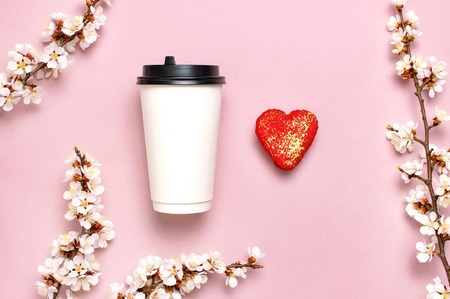 Coffee or tea paper cup, heart-shaped macaroon cakes, spring branches of white flowers on pink background top view flat lay. Take away coffee cup, mockup. Coffee love concept, layout for design.の写真素材