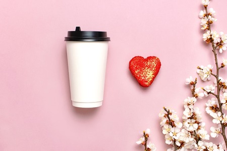 Coffee or tea paper cup, heart-shaped macaroon cakes, spring branches of white flowers on pink background top view flat lay. Take away coffee cup, mockup. Coffee love concept, layout for design.の写真素材