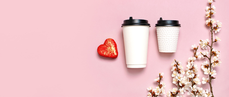 Coffee or tea paper cup, heart-shaped macaroon cakes, spring branches of white flowers on pink background top view flat lay. Take away coffee cup, mockup. Coffee love concept, layout for design.の写真素材