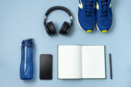 Mens  sneakers, bottle of waters, smartphone, headphone, notebook diary with marker on  background.の写真素材