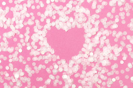 Frame shape of heart from paper round confetti on pastel pink background Flat lay top view. Festive holiday background, concept of party, birthday, christmas or new year. Copyspace for text.の写真素材
