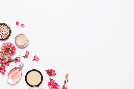 Different makeup cosmetic. Ball blush rouge face powder lipstick concealer bottle of perfume eyeshadow makeup brush spring pink flowers on light background top view flat lay. Beauty fashion background.の写真素材