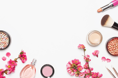 Different makeup cosmetic. Ball blush rouge face powder lipstick concealer bottle of perfume eyeshadow makeup brush spring pink flowers on light background top view flat lay. Beauty fashion background.の写真素材