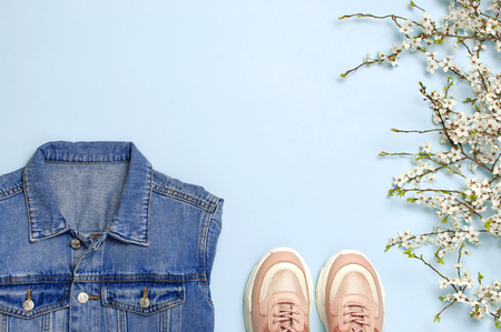 Blue denim jacket, trendy pink sneakers, spring flowers on blue background top view flat lay copy space. Denim, fashionable jacket, women's or men's trend clothing, Spring fashion beauty backgroundの写真素材