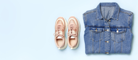 Blue denim jacket and trendy pink sneakers on blue background top view flat lay copy space. Denim, fashionable jacket women's or men's trend clothing, fashion beauty background. Spring Fashion Concept.の写真素材