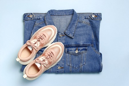 Blue denim jacket and trendy pink sneakers on blue background top view flat lay copy space. Denim, fashionable jacket women's or men's trend clothing, fashion beauty background. Spring Fashion Concept.の写真素材