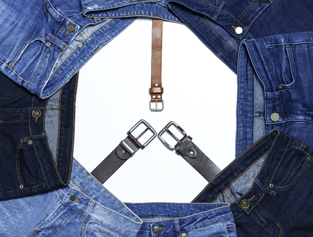 Frame of different blue jeans and leather belts isolated on white background top view flat lay. Detail of nice blue jeans. Jeans texture or denim background. Trend clothing. Beauty and fashion.の写真素材