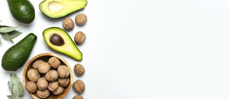 Ripe fresh avocado, walnuts in wooden bowl, eucalyptus twigs on white background top view Flat lay copy space. Fruits Healthy food concept, diet, healthy lifestyleの写真素材