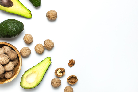Ripe fresh avocado and walnuts in wooden bowl on white background top view Flat lay copy space. Fruits Healthy food concept, diet, healthy lifestyleの写真素材
