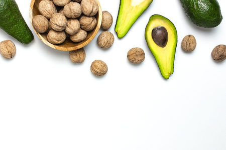 Ripe fresh avocado and walnuts in wooden bowl on white background top view Flat lay copy space. Fruits Healthy food concept, diet, healthy lifestyleの写真素材